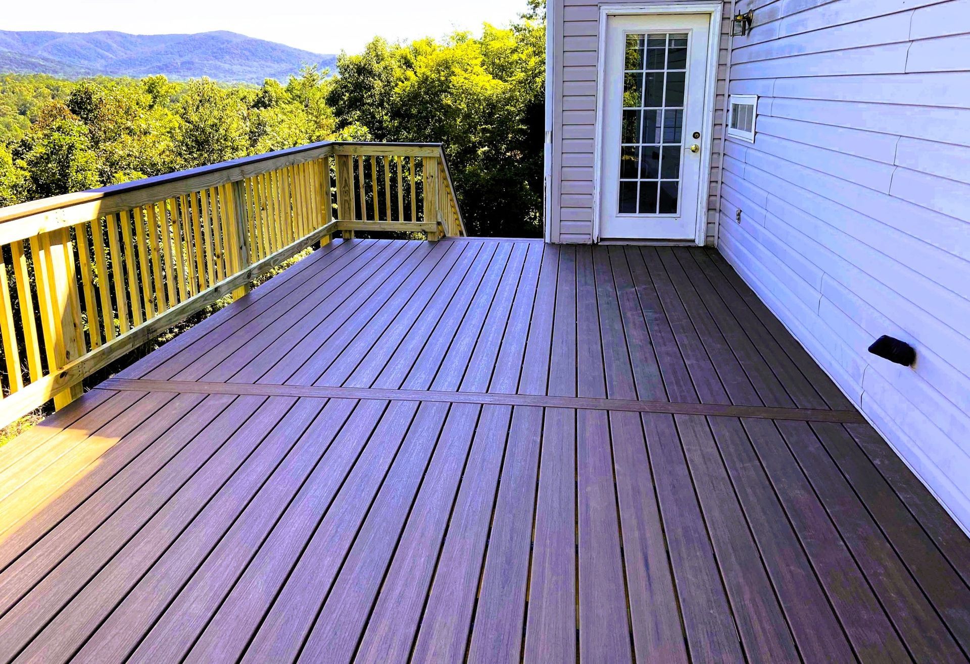 Two-storey rear deck with wood baluster railing above and wire mesh infill screening the covered level below