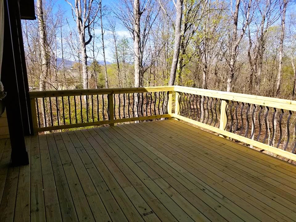 Pressure-treated deck with curved black decorative balusters facing distant blue mountains through bare spring trees