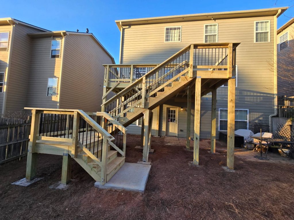 Tall deck with black aluminum balusters and two stair landings stepping down to a concrete pad