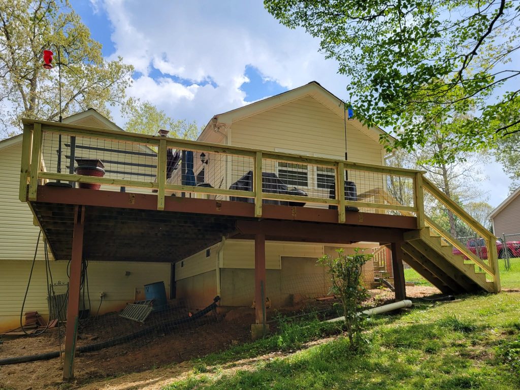 Repaired elevated deck with new wire mesh railing and boards set on retained older support posts