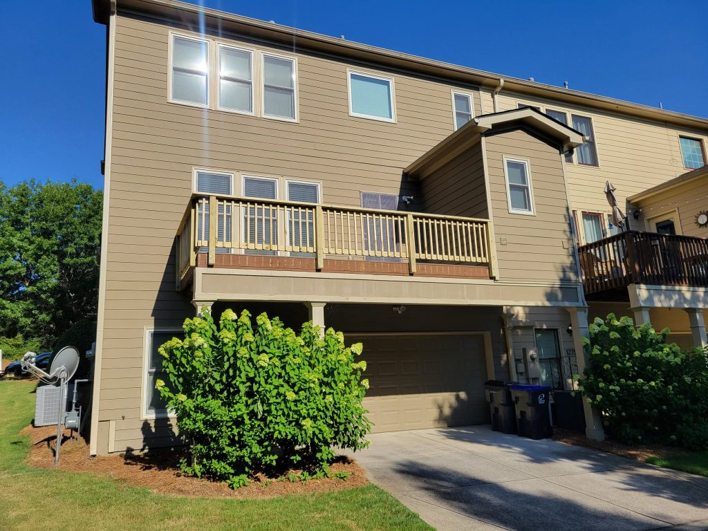 New second-storey townhouse balcony deck with wood baluster railing above the garage
