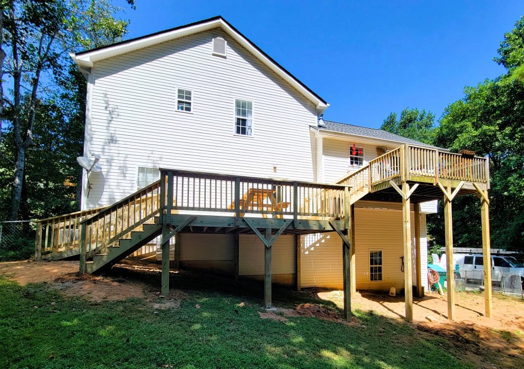 Tall pressure-treated deck on a white house with a long angled stair run down to the lawn