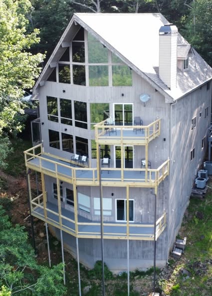 Aerial view of a three-level Trex deck wrapping a tall A-frame home on a wooded slope